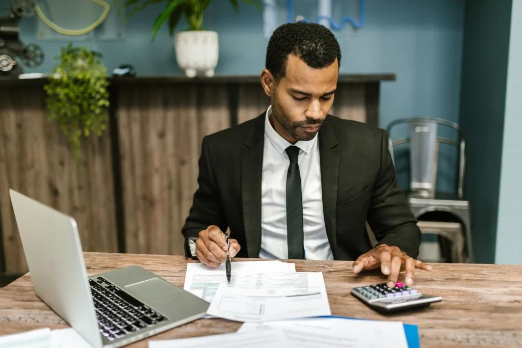 Gestionnaire de paie concentré travaillant avec une calculatrice et des documents dans un bureau moderne