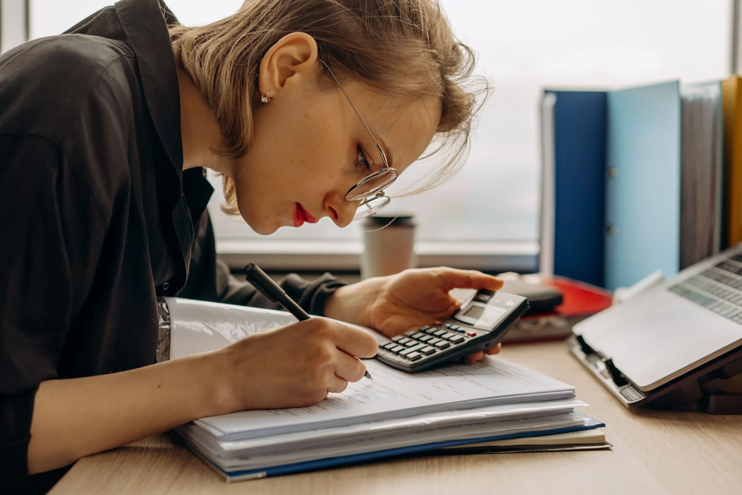 Gestionnaire de paie travaillant sur les fiches de paies avec une calculatrice et des documents